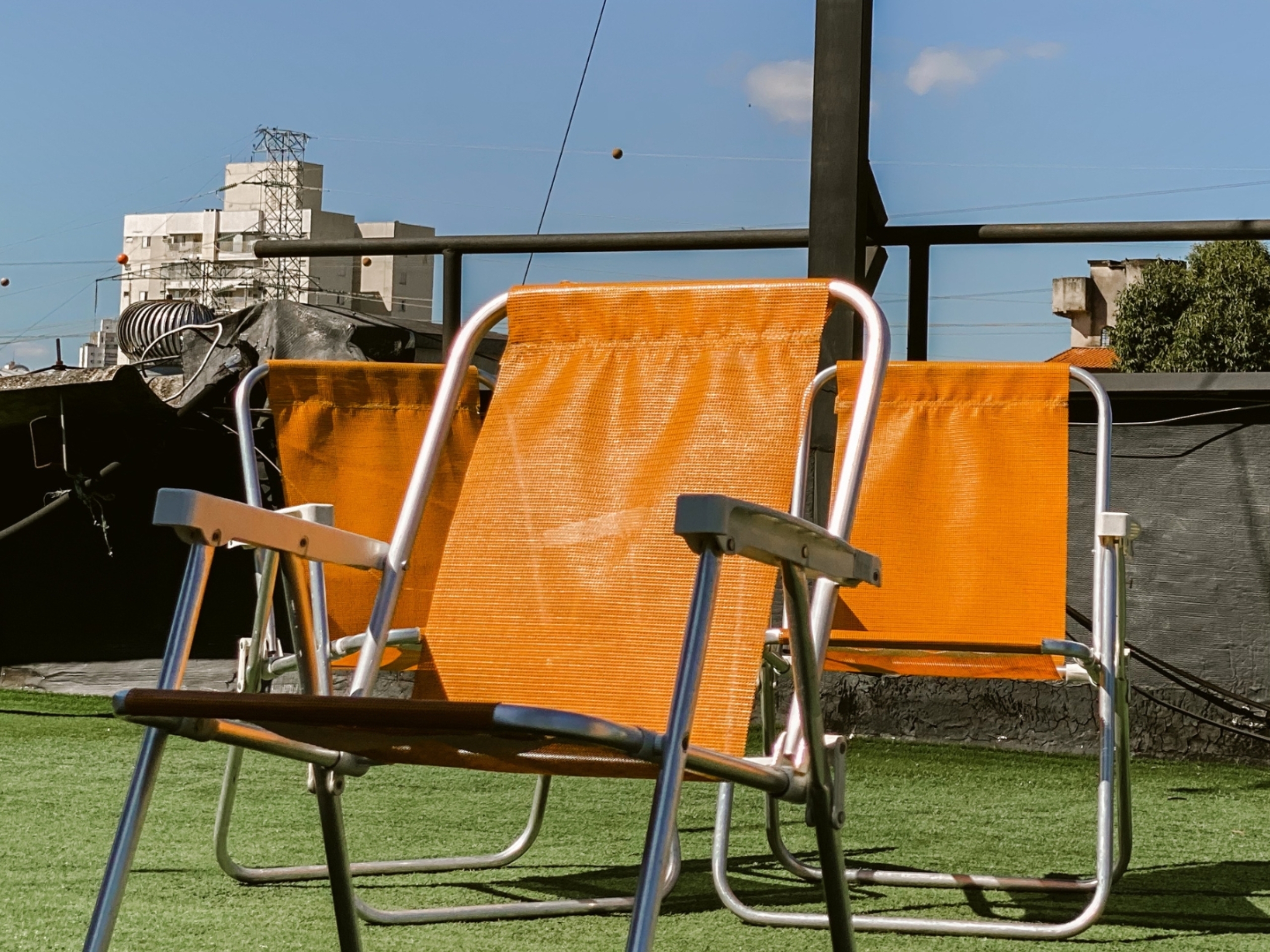 Orange Coworking Espaço para Eventos 4 Cadeiras de praia laranjas no terraço com grama sintética do Orange Coworking. Área externa de descanso e convivência com vista da cidade.